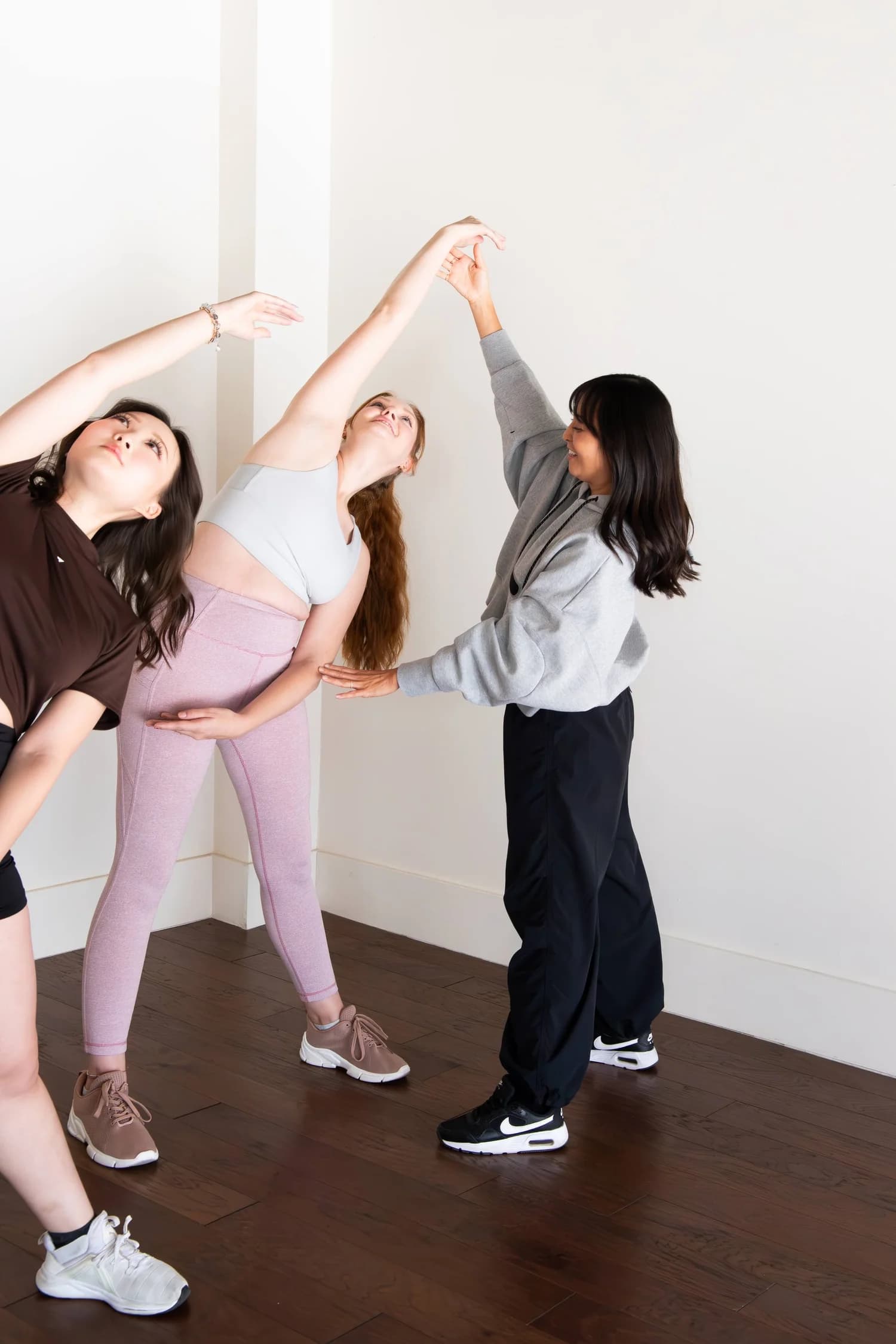 An Ebb & Flow instructor guiding two adults through a side stretch